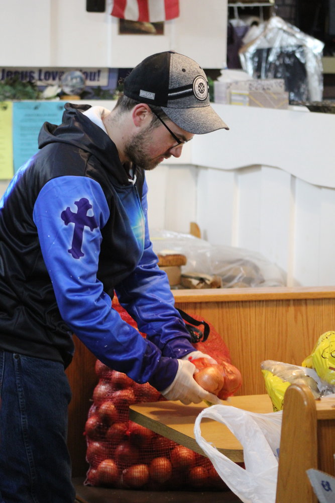 Chris, a volunteer at the food pantry, gets the onions sorted for distribution.